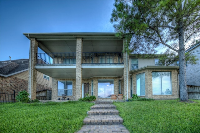 view of front of house with brick siding, a balcony, and a front lawn