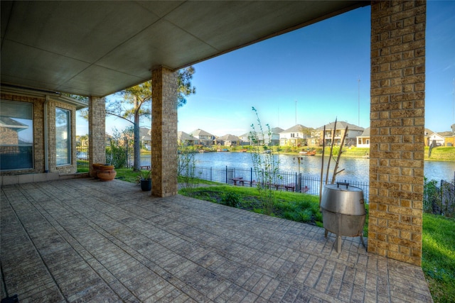 view of patio / terrace with a water view, a residential view, and fence