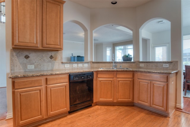 kitchen with light stone counters, a sink, backsplash, dishwasher, and light wood finished floors