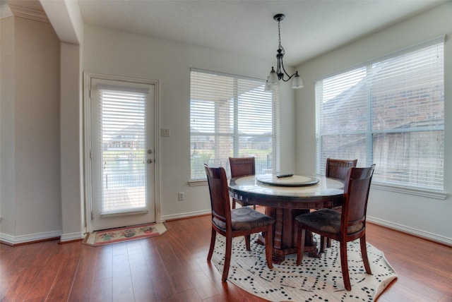 dining space with baseboards, wood finished floors, and an inviting chandelier