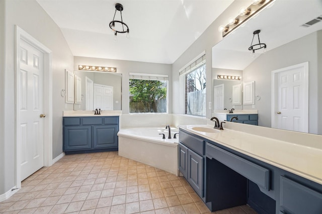 bathroom featuring a bath, two vanities, a sink, and visible vents