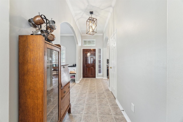 entrance foyer featuring light tile patterned floors, baseboards, visible vents, arched walkways, and ornamental molding