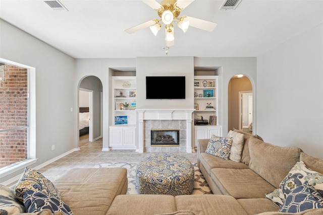 living room featuring light tile patterned floors, a fireplace, visible vents, and built in features