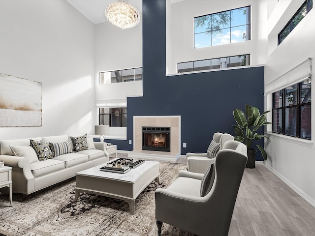 living area with a tile fireplace, a high ceiling, baseboards, and wood finished floors