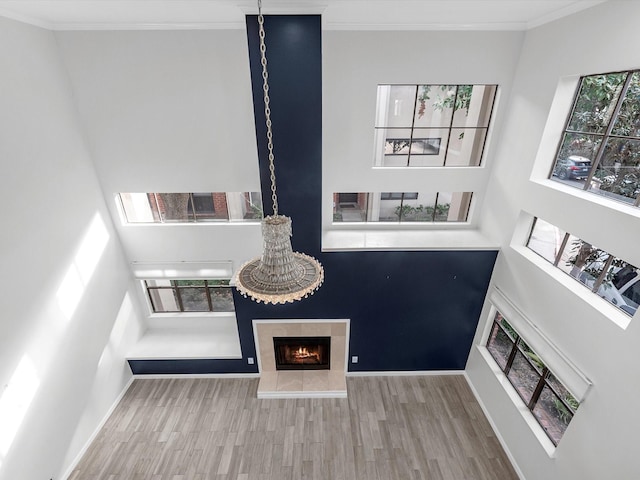 living room with light wood-style flooring, baseboards, crown molding, and a tile fireplace