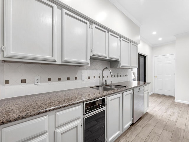 kitchen featuring dark stone countertops, white cabinets, a sink, and dishwasher