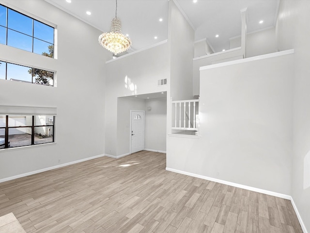 unfurnished living room with baseboards, visible vents, ornamental molding, light wood-style floors, and a chandelier