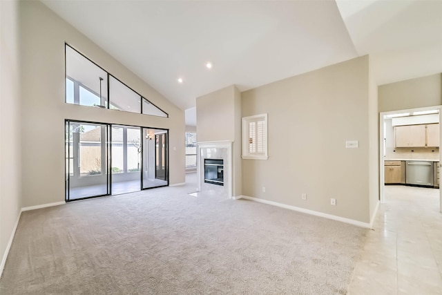 unfurnished living room with high vaulted ceiling, a fireplace, baseboards, and light colored carpet