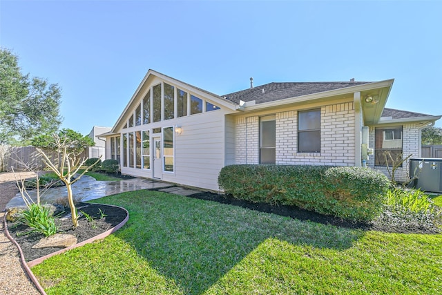 back of house featuring central AC, fence, a lawn, and brick siding