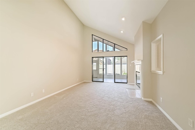 empty room with light carpet, high vaulted ceiling, recessed lighting, and baseboards