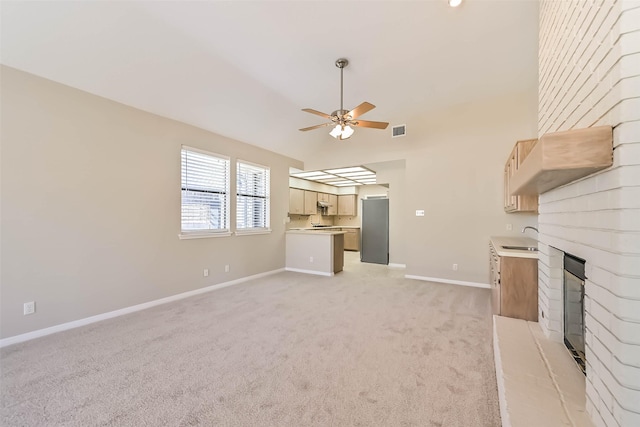 unfurnished living room with ceiling fan, light colored carpet, a fireplace, visible vents, and baseboards