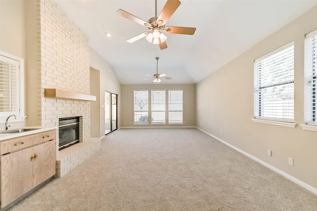 unfurnished living room featuring a healthy amount of sunlight, a brick fireplace, light carpet, and a sink