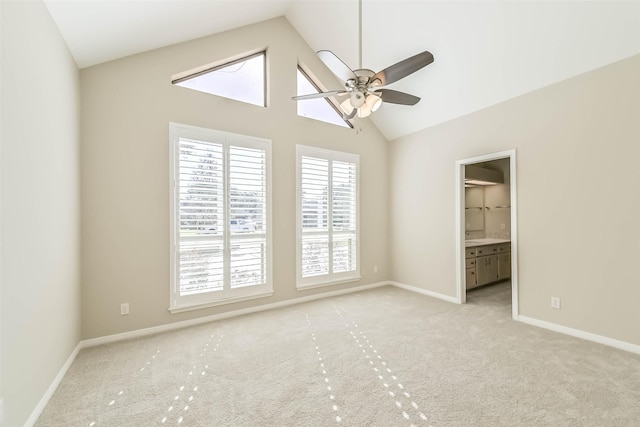 spare room with a ceiling fan, light carpet, high vaulted ceiling, and baseboards