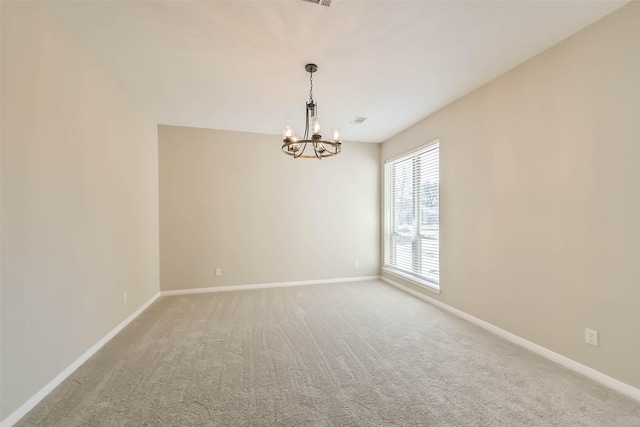 carpeted spare room with a chandelier, visible vents, and baseboards