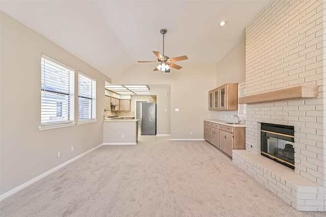 unfurnished living room featuring light carpet, a fireplace, a ceiling fan, baseboards, and vaulted ceiling