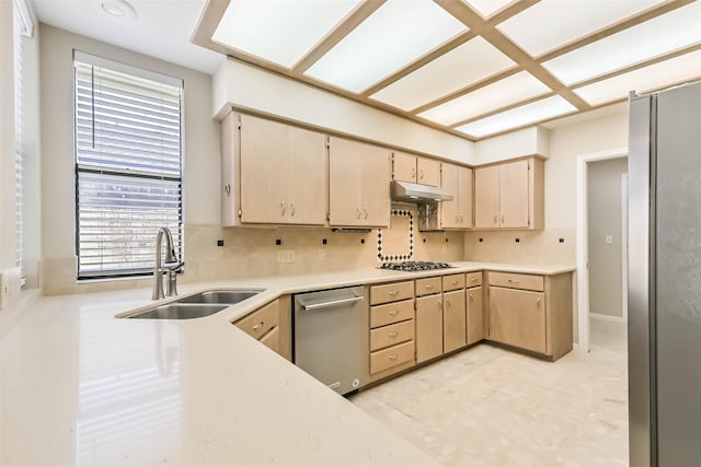 kitchen featuring under cabinet range hood, stainless steel appliances, a sink, light countertops, and decorative backsplash