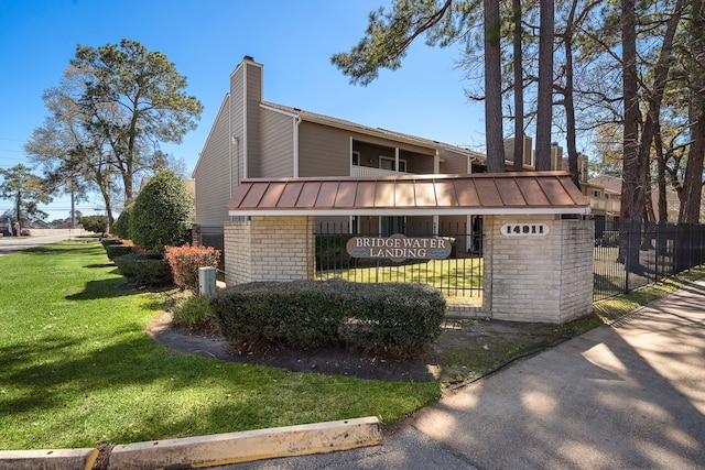 view of property exterior featuring a lawn, a standing seam roof, fence, metal roof, and a chimney