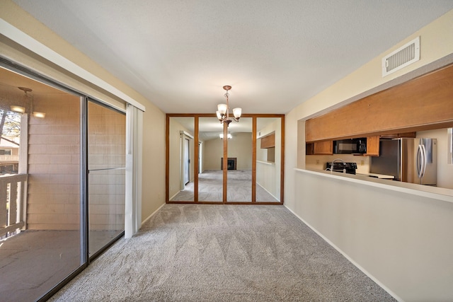 unfurnished dining area with visible vents, baseboards, a chandelier, light carpet, and a textured ceiling