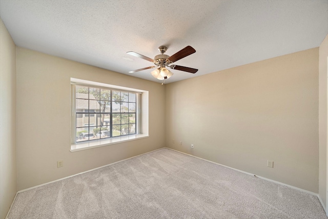 carpeted spare room with baseboards, a textured ceiling, and a ceiling fan