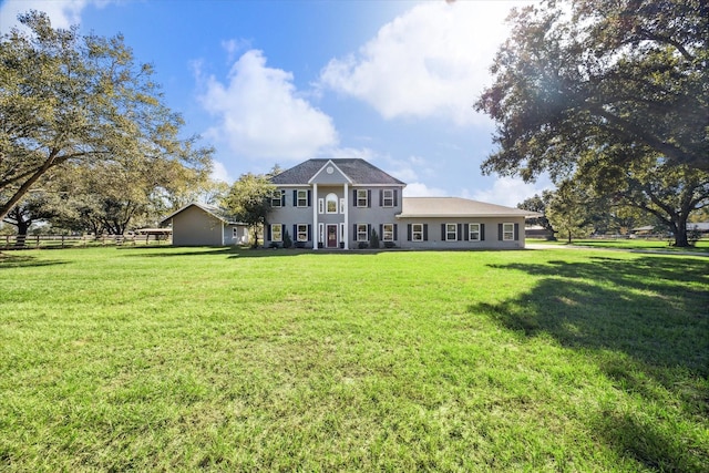 rear view of property featuring a yard and fence