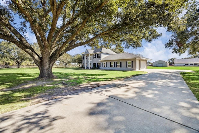 view of front of house featuring driveway, a front lawn, an attached garage, and fence