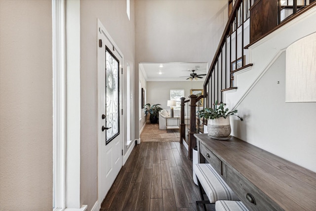 entryway featuring dark wood-type flooring, stairway, a towering ceiling, and crown molding