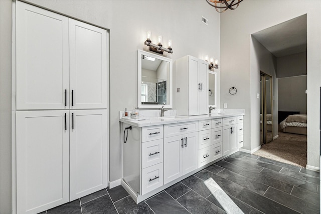 bathroom with double vanity, visible vents, ensuite bathroom, a sink, and baseboards