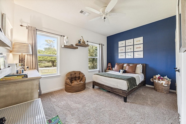 carpeted bedroom featuring baseboards, multiple windows, visible vents, and ceiling fan