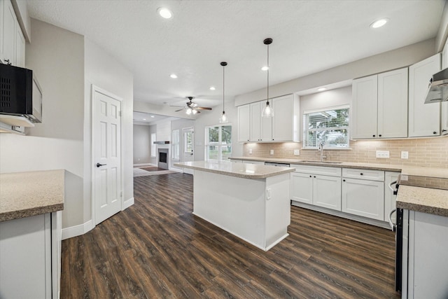 kitchen featuring white cabinets, a sink, decorative light fixtures, and a center island