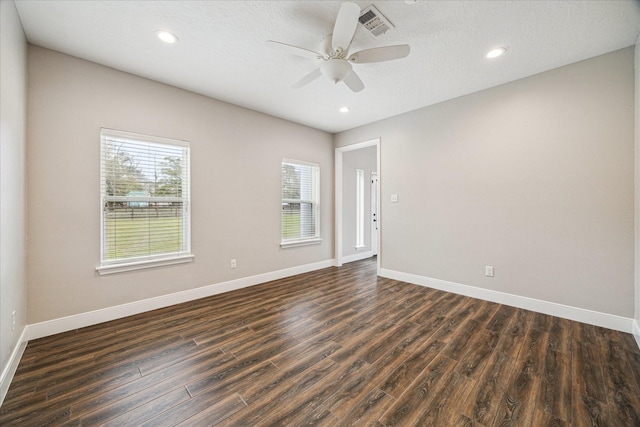 spare room with ceiling fan, dark wood-type flooring, visible vents, and baseboards