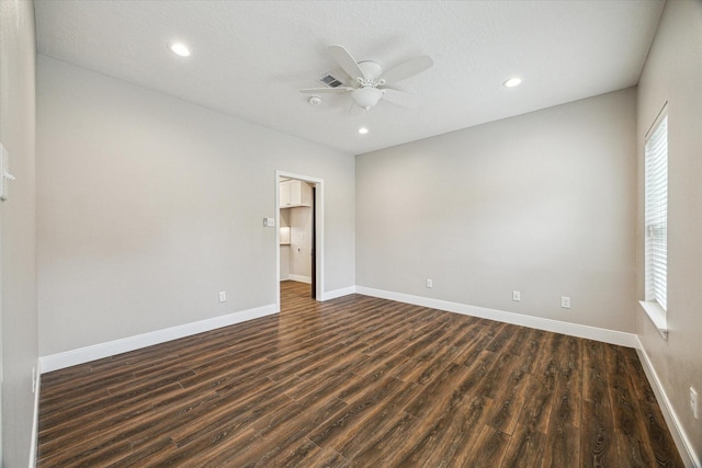 spare room with a ceiling fan, recessed lighting, dark wood finished floors, and baseboards