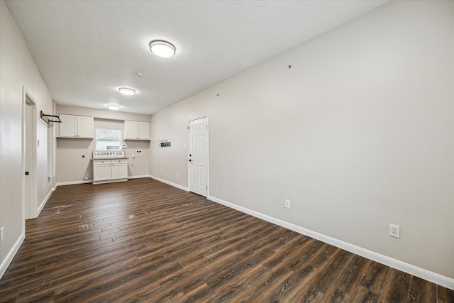 kitchen with a textured ceiling, dark wood-style flooring, baseboards, white cabinets, and light countertops