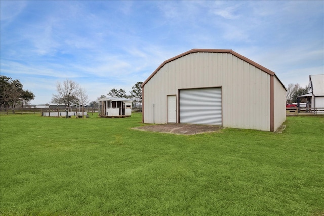 view of outdoor structure featuring driveway, fence, and an outbuilding