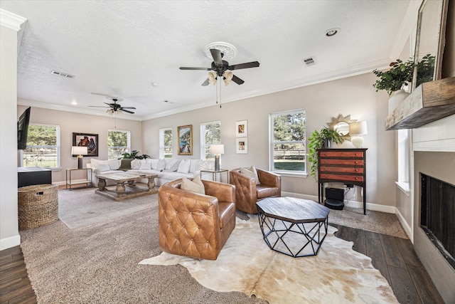 living area with a textured ceiling, visible vents, wood finished floors, and ornamental molding