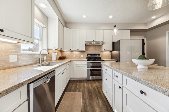 kitchen featuring decorative light fixtures, appliances with stainless steel finishes, white cabinets, a sink, and under cabinet range hood