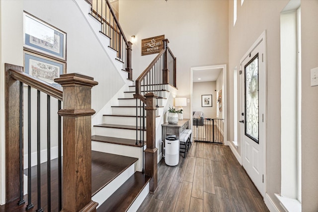 entrance foyer featuring stairway, dark wood finished floors, a towering ceiling, and baseboards