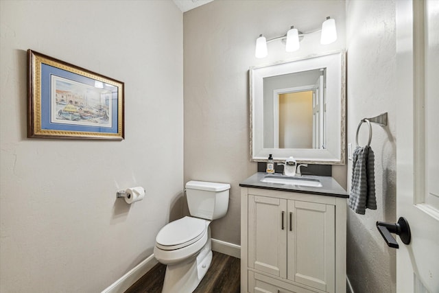 bathroom with baseboards, vanity, toilet, and wood finished floors