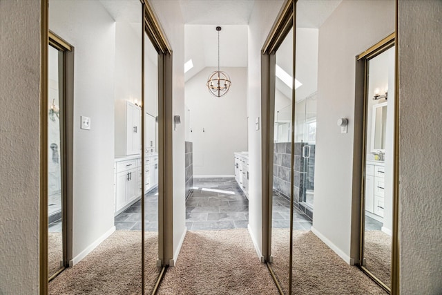 corridor with carpet floors, high vaulted ceiling, baseboards, and a chandelier