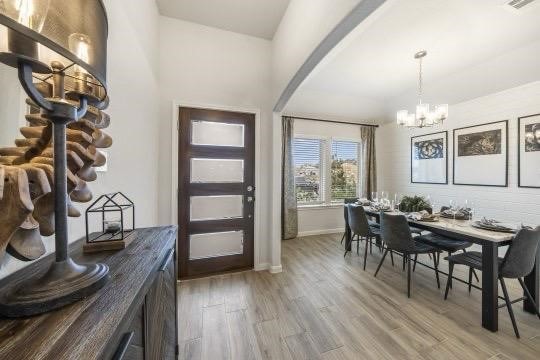 entrance foyer with arched walkways, wood finished floors, visible vents, baseboards, and an inviting chandelier