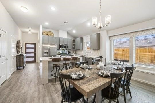 dining area with a notable chandelier, lofted ceiling, recessed lighting, wood finished floors, and baseboards