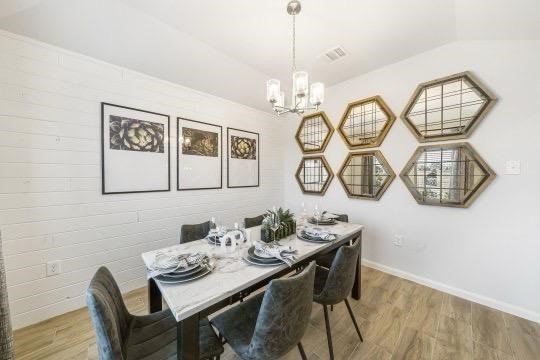 dining room with visible vents, a notable chandelier, baseboards, and wood finished floors