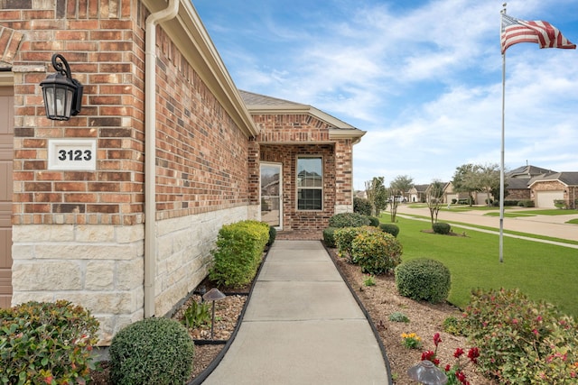 doorway to property featuring brick siding and a lawn