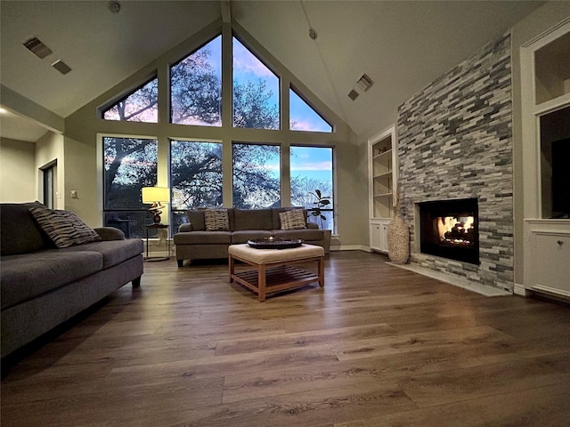 living area with built in features, visible vents, dark wood finished floors, and a stone fireplace