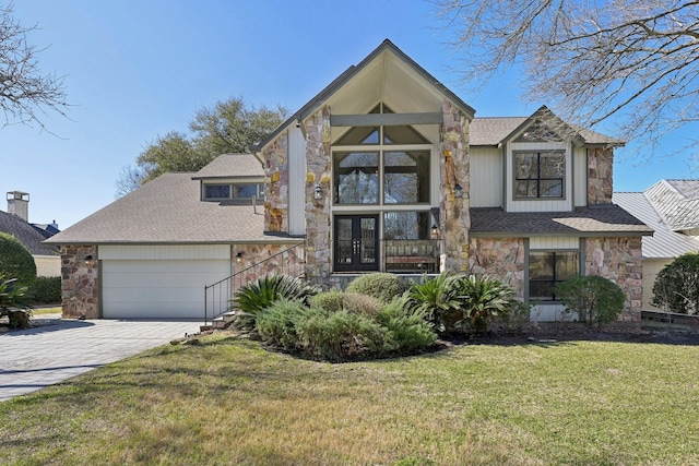 view of front of property featuring stone siding, french doors, decorative driveway, and a front yard