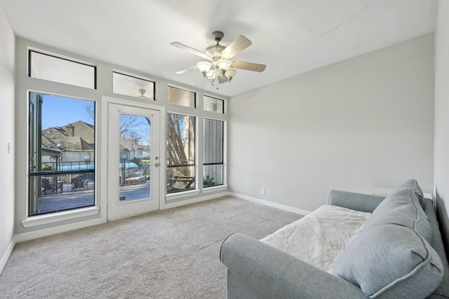 living room with light carpet, a ceiling fan, and baseboards