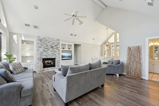 living area with a fireplace, wood finished floors, visible vents, and built in features