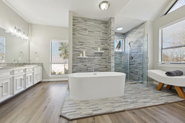 bathroom with a freestanding bath, wood finished floors, vanity, and a shower stall