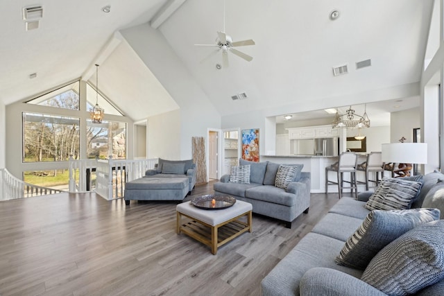 living room featuring light wood-style floors, visible vents, beamed ceiling, and high vaulted ceiling