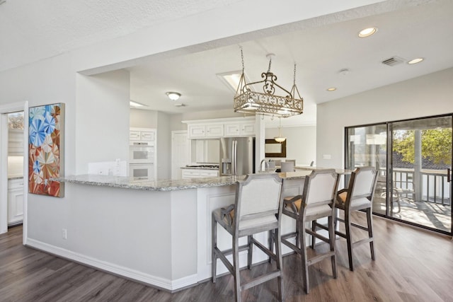 kitchen featuring a peninsula, stainless steel fridge, a breakfast bar, and white cabinets