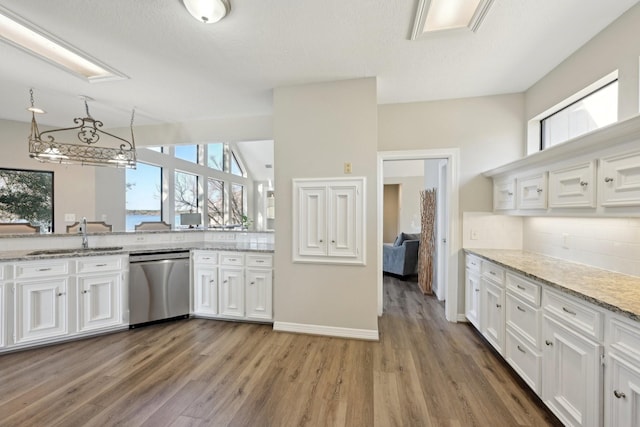 kitchen featuring dishwasher, backsplash, light stone countertops, white cabinetry, and a sink